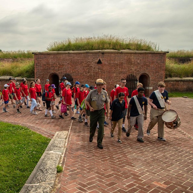 A park ranger leading a group of kids during Fort McHenry band camp.