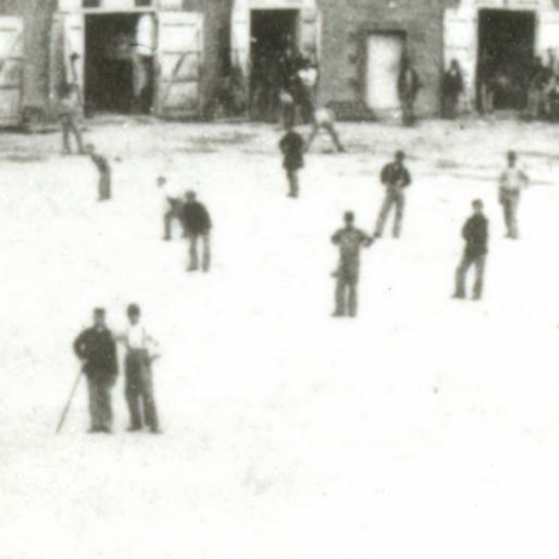 While a group of soldiers are at attention in front, a game of baseball is played in the back.