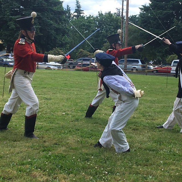 Costumed volunteers practicing with sabers on the Great Meadow.