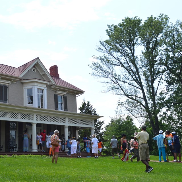 A group of visitors in front of a historic house
