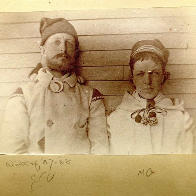 Black and white of man and woman wearing winter gear. 