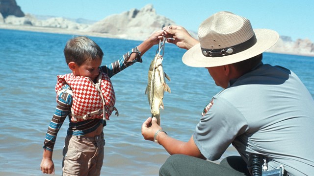 Ranger measures a fish held by a child in a lifejacket