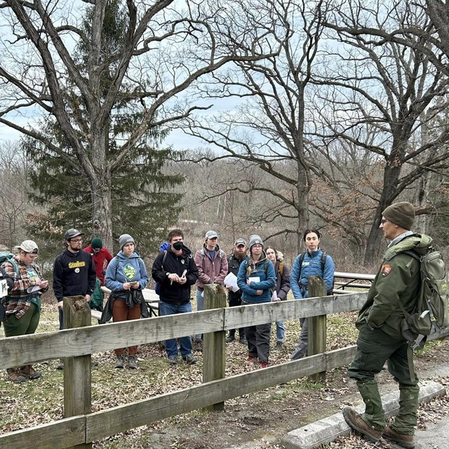 Ranger in uniform standing and facing a group of young adults