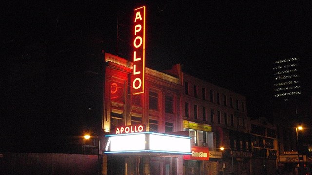 The neon red sign for the Apollo Theater shines in the darkness.
