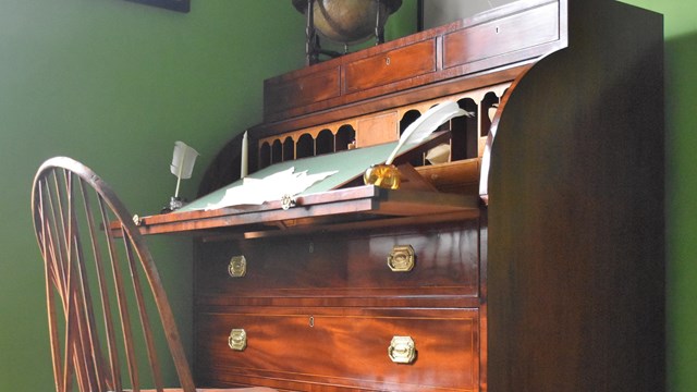 A mahogany 19th-century desk with a feather pen upon it.