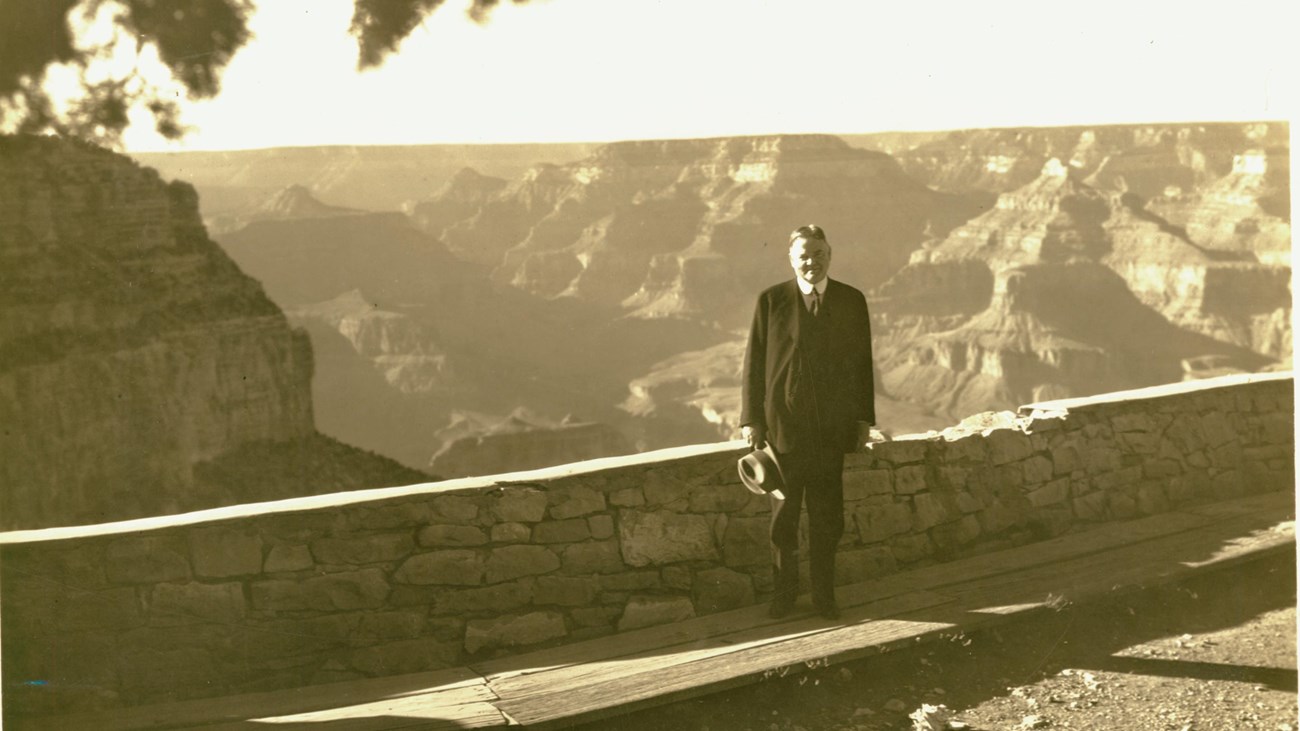 Sepia photo of Herbert Hoover standing at the rim of the Grand Canyon.