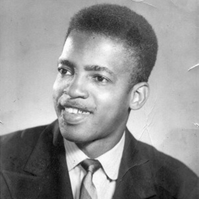 Portait of a young black man, looking slightly to the right and smiling.