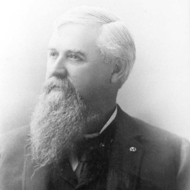 Portrait from 1900s, an elderly gentleman with a long beard looks off in the distance.
