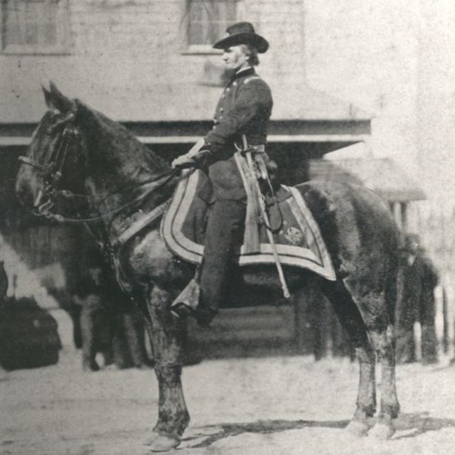 A man wearing a ranger uniform on a large horse, circa late 1800s.