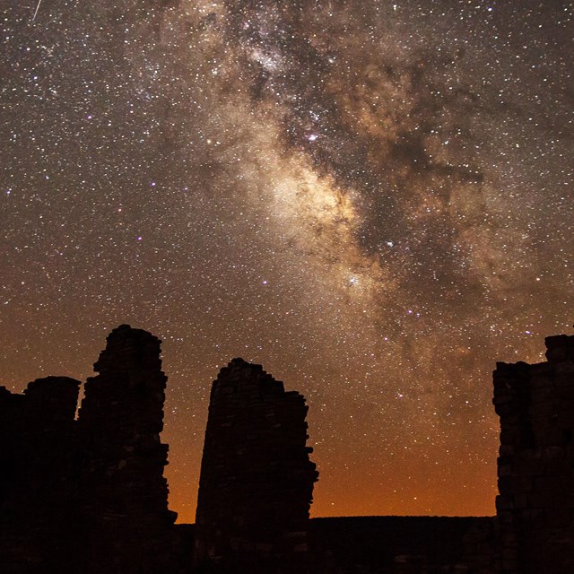 silhouetted structures with the night sky and Milky Way overhead.