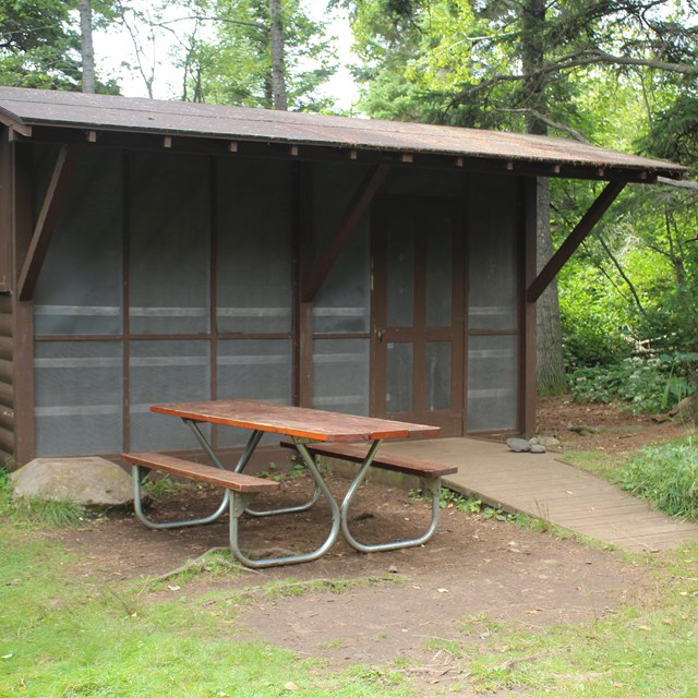 Campground shelter with picnic table and ramp at Daisy Farm Campground at Isle Royale. 