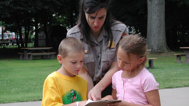 a park ranger looking over an activity with a young boy and girl