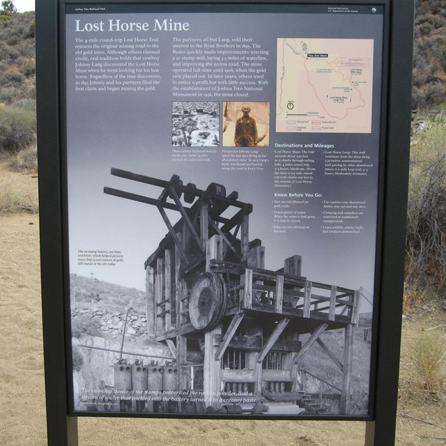 An education sign at a trailhead with a desert landscape in the background