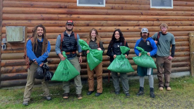 Student Conservation Crew holding garbage bags full of invasive plants.