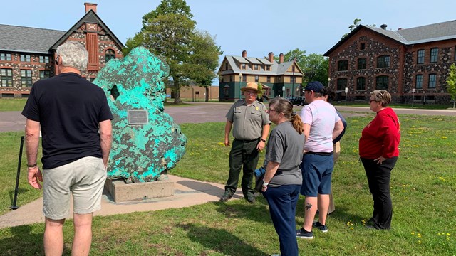 A ranger giving a talk to visitors in front of a copper exhibit.