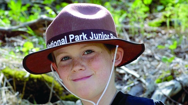Boy wearing a brown hat with the words, Junior Ranger. 