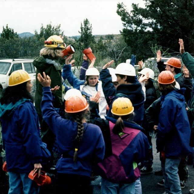 A school group in hard hats standing around a park ranger