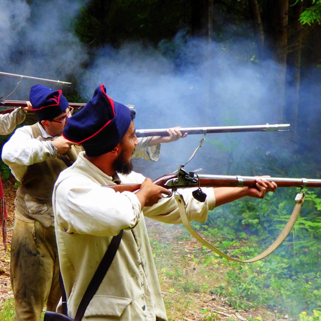 Four rangers in a line shooting black powder muzzle loaders
