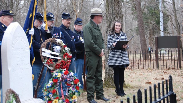 People in Civil War uniforms, park ranger and woman behind gravestone of Nancy Lincoln