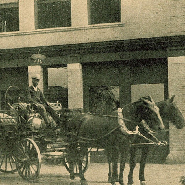 Firemen stand in front of a fire carriage
