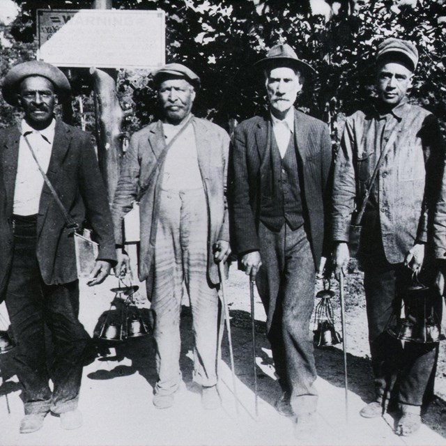 Black and white photo of five men standing for the camera.