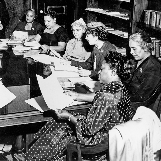 Women seated around a table looking at papers.