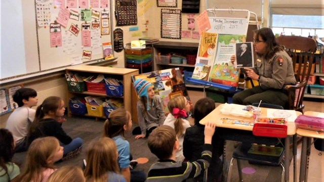 Park ranger reading a book to a classroom of children 