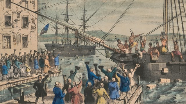 A crowd gathers on a wharf to cheer men tossing chests of tea off of ships into Boston Harbor.