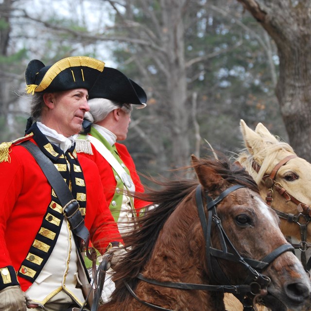 Two British officers in scarlet red coats ride horses