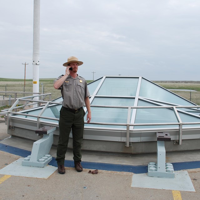 Ranger standing next to a missile silo listening to a tour on his cell phone