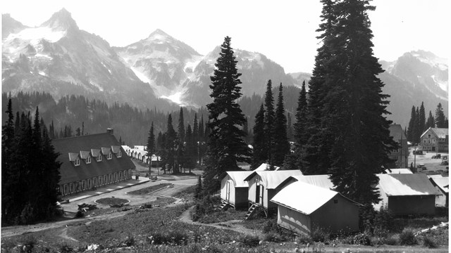 A cluster of tent cabins next to a large wood building on the subalpine meadow slopes. 