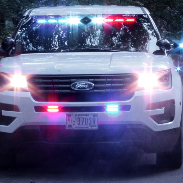 A front view of a white SUV with blue and red flashing lights.