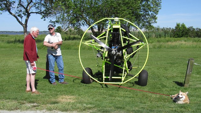 two men standing near a paraglider near a road