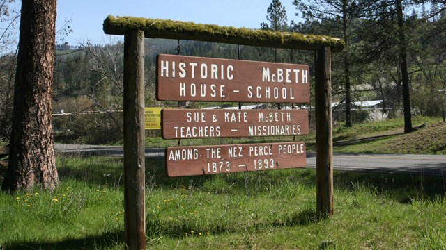 A dark brown sign with the words 'Historic McBeth House - School' on it.