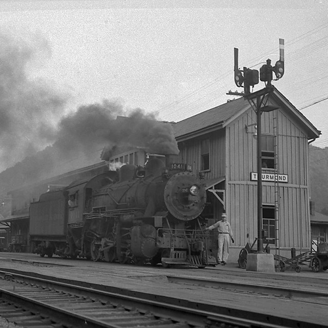 black and white photo of steam engine and railroad depot