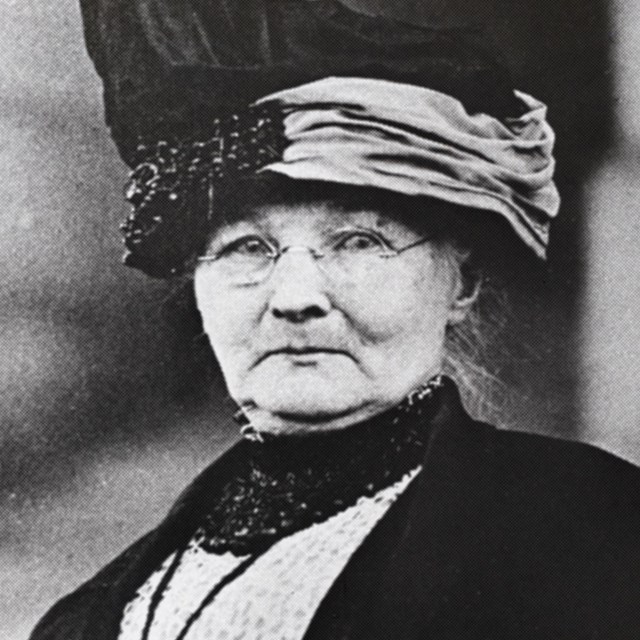 black and white photo of an older woman in a worn Victorian dress