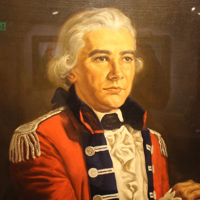 A man in a white wig and red coat with blue facing. 