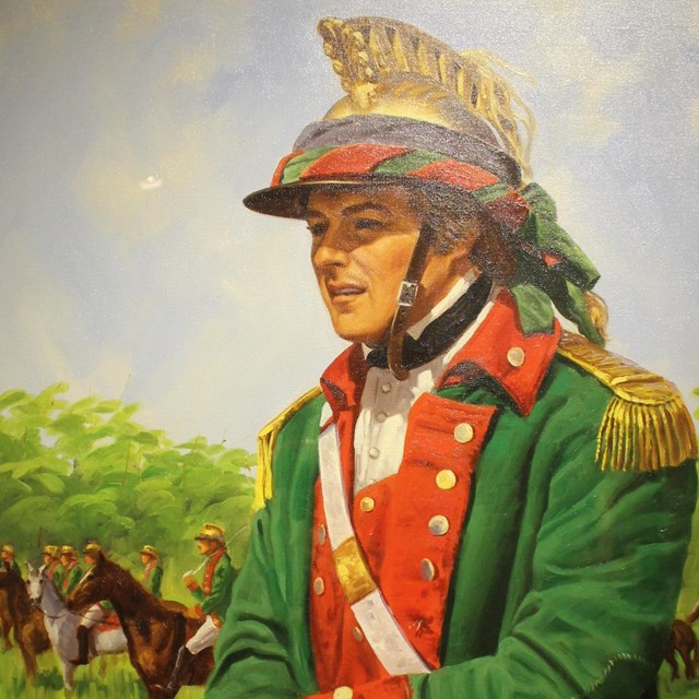 A man with a black hat in a green coat with red facing atop a horse. 