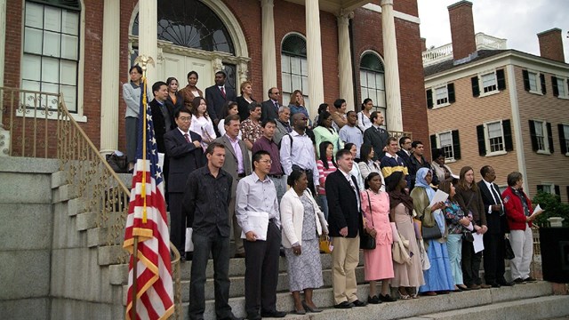 Group of people in a citizenshop ceremony on the steps of a historic building 