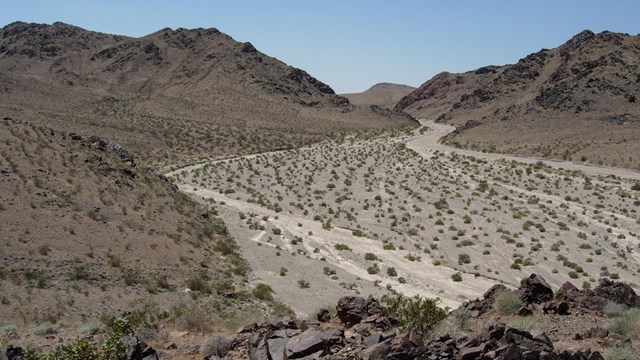A remote desert wash, surrounded by rocky hills void of vegetation.