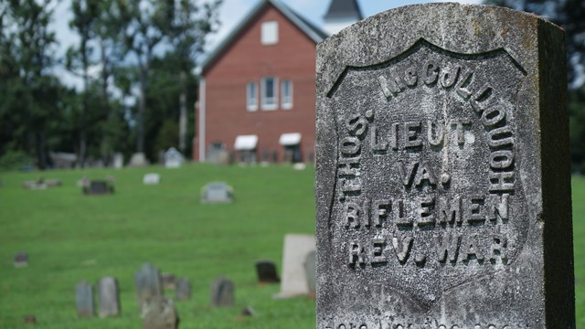 Stone tombstone in front of a brick church