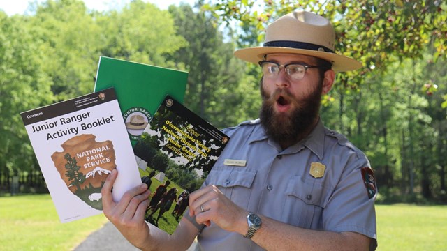 Ranger holds three Junior Ranger books