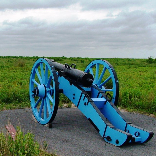 Replica cannon with a blue carriage overlooking the battlefield.