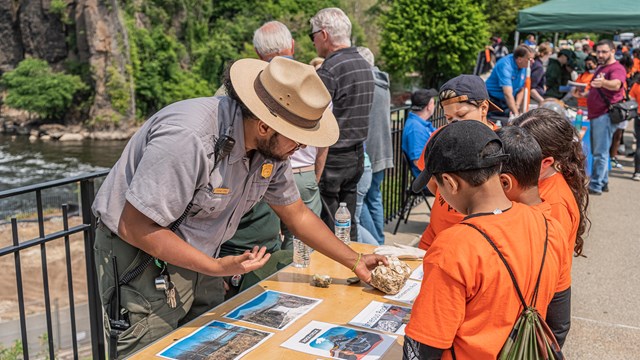 A park ranger shows different rocks to a group of children