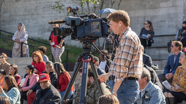 A news crew films at an outdoor ampitheater