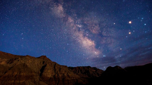 View of the Milky Way over Parashant against a rugged skyline of Whitmore Canyon.