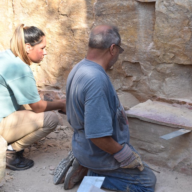 A man and woman analyzing stone in a quarry pit