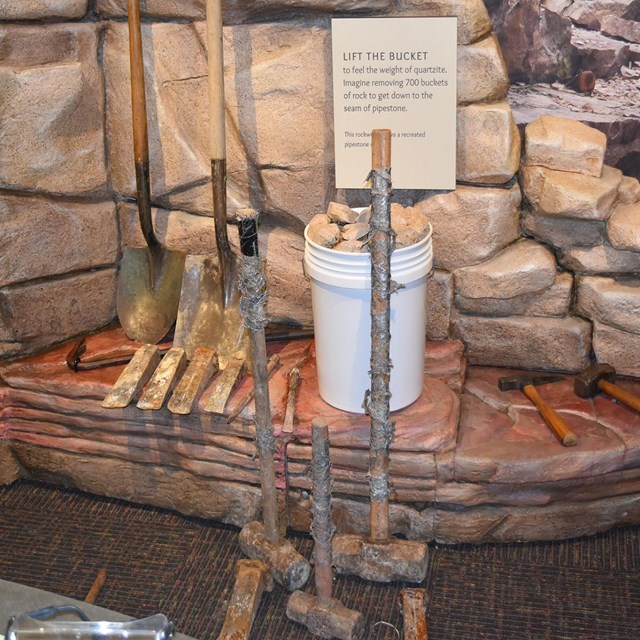 Tools lined up against an exhibit of a stone wall