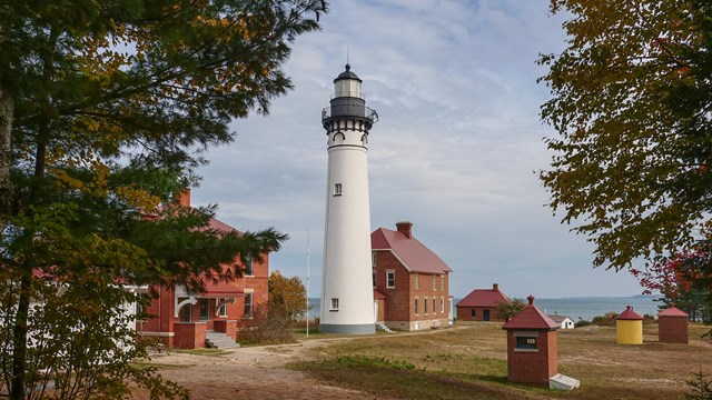 A white lighthouse tower surrounded by red brick buildings