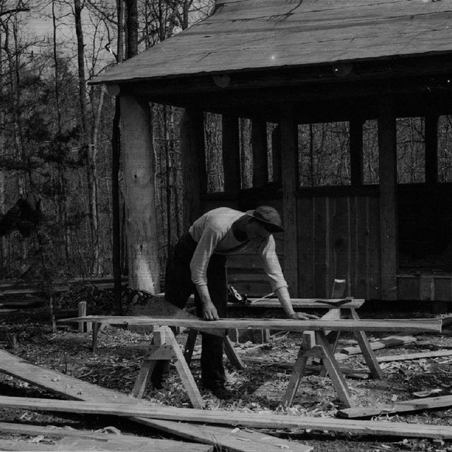 Historic photo of a CCC man building a cabin